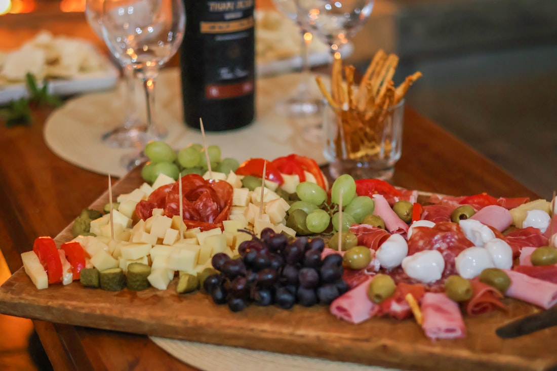 Planche de dégustation : fromages, viandes séchées, raisins et vin