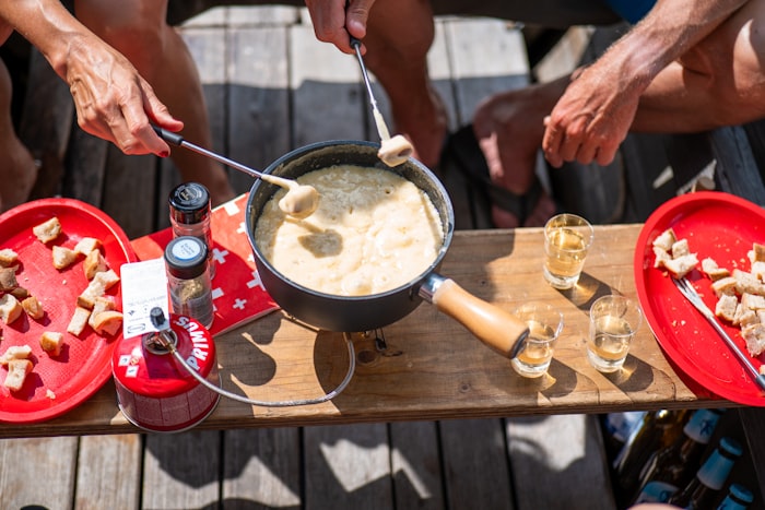 Pain trempé dans un caquelon de fondue au fromage